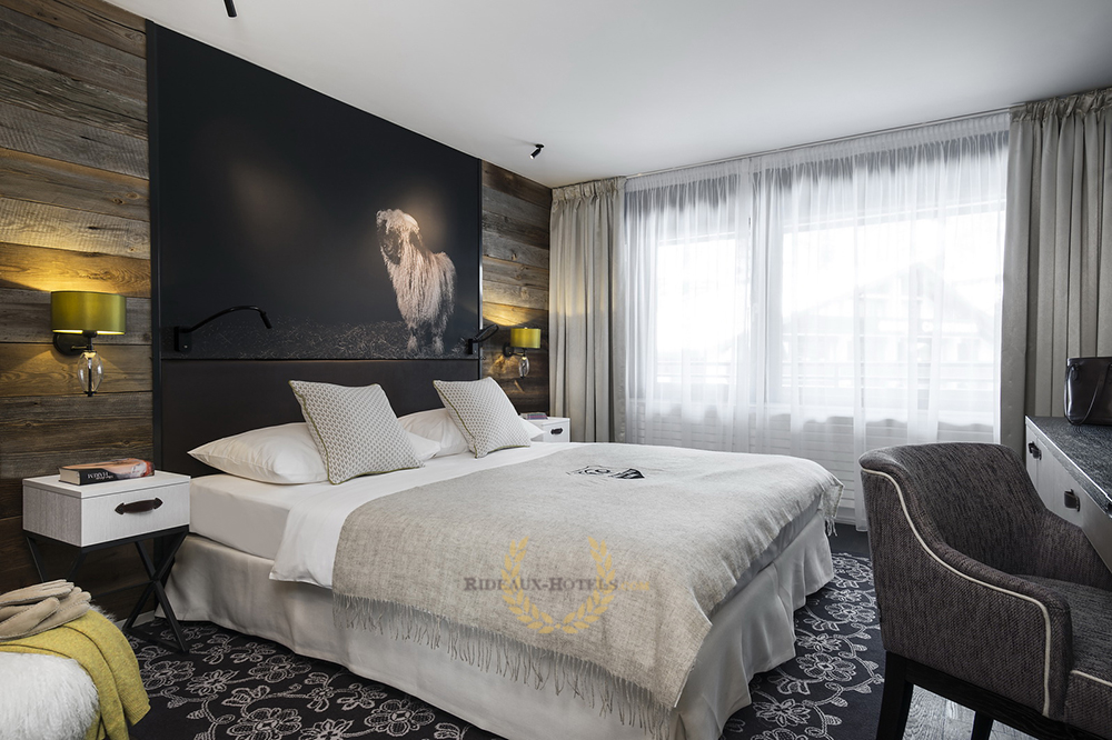 Chambre de luxe aménagé avec des rideaux occultant et voilage tamisant ignifugés non feu M1